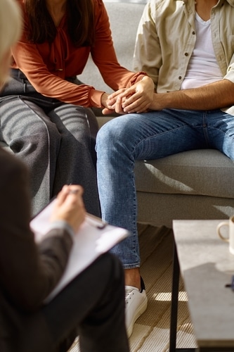Two people hold hands during a counseling session.